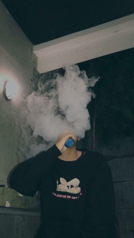 Individual using an electronic cigarette, with a backdrop of Backpackboyz vape products and diverse flavor options.